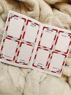 an open planner with red and white stripes on it sitting on a pile of blankets