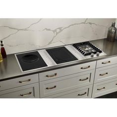 a stove top oven sitting on top of a counter next to white drawers and cabinets