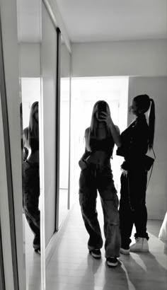 two women standing in front of a mirror