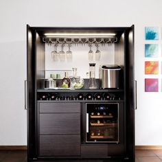 a small bar with wine glasses and bottles on the top shelf in a room that has tile flooring