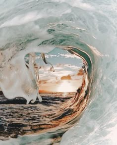 an ocean wave is seen through the center of it's tube, with light reflecting on the water