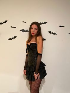 a woman in a black dress with bats on the wall behind her is posing for a photo