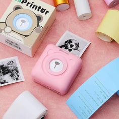 a pink camera sitting on top of a table next to some rolls of tape and other items