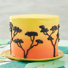 an orange and yellow cake with black decorations on the top is sitting on a table