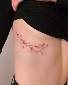 a woman's stomach has a small branch tattoo on it