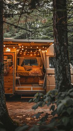 a camper van is parked in the woods with its doors open and lights on