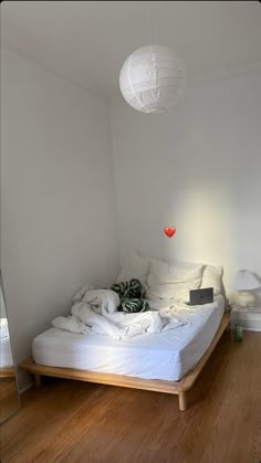 a white bed sitting on top of a hard wood floor next to a wall mounted mirror