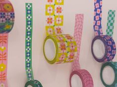 several rolls of washi tape are hanging on the wall next to flowers and checkered ribbons