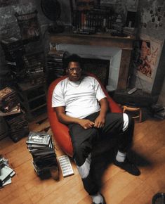 a man sitting in a red chair with his feet up on the floor next to a fireplace