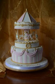 a three tiered carousel cake with pink and white icing