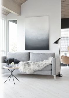 an image of a living room with white walls and grey furniture, including a gray couch