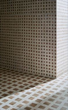 a white and brown checkered wall in a room with sunlight coming through the window