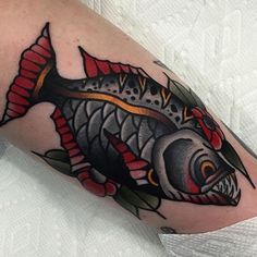 a fish tattoo on the arm with red and black colors is seen in this image