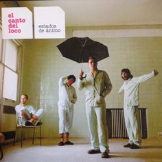 the four men are standing in an empty room with an umbrella over their heads, and one man is pointing at something