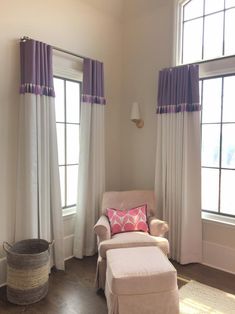 a chair and ottoman in front of two windows with purple drapes on the curtains