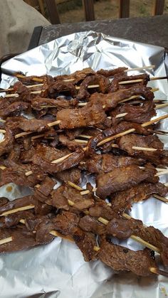 skewers of meat sitting on top of aluminum foil