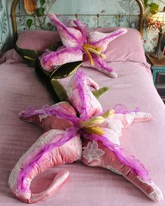 two decorative pillows laying on top of a pink bed