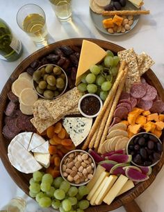 an assortment of cheeses, crackers, and grapes on a platter