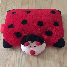 a red and black ladybug rug laying on the floor next to a toy