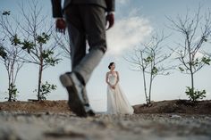 a woman in a wedding dress standing next to a man with his foot on the ground