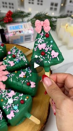 a woman is decorating christmas cookies on a wooden platter with pink and green decorations