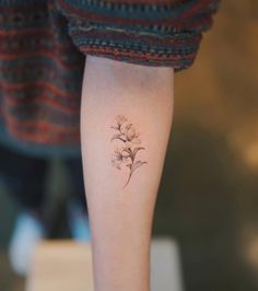 a small flower tattoo on the right arm and leg, is shown in this image