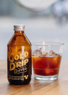 a bottle of cold coffee next to a glass with ice