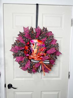 a pink and black wreath hanging on the front door to a white door with an image of a woman's face