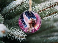 a glass ornament hanging from a christmas tree with an angel painted on it