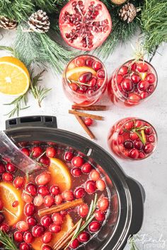 cranberry orange punch in a slow cooker surrounded by christmas decorations and pine cones