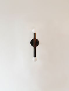 a white wall with a black and silver light fixture on it's left side