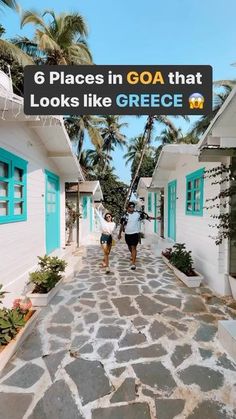 two people walking down the street in front of white houses with blue shutters and palm trees