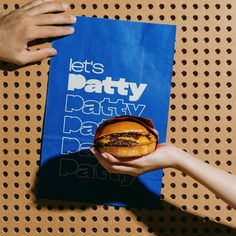 two hands holding a burger in front of a party book on a table with polka dots