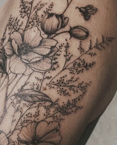 a black and white photo of flowers on the side of a woman's thigh