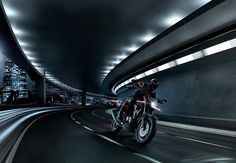 a man riding a motorcycle down a tunnel in the middle of city at high speeds