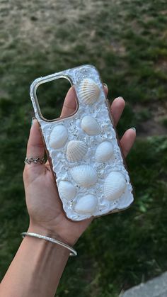 a person holding up a cell phone case with shells on the front and back cover