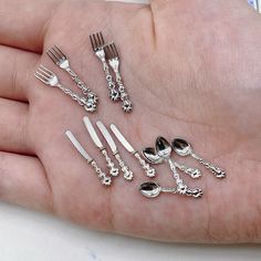 a person's hand holding several different types of forks and spoons on it