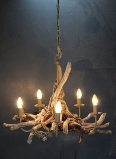 a chandelier made out of driftwood with five lit candles on each branch