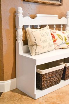 a white bench with two baskets under it and a painting on the wall behind it