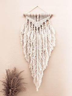 a white wall hanging next to a potted plant