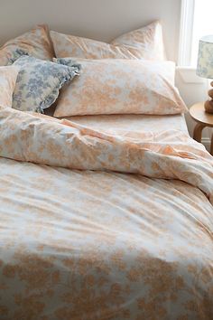 an orange and white bed in a bedroom next to a table with two lamps on it