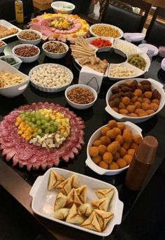 a table filled with lots of different types of food on plates and bowls next to each other