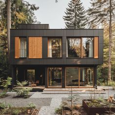 a modern house in the woods with lots of windows and wood sidings on it