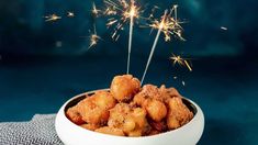 a white bowl filled with fried food on top of a blue table cloth next to a sparkler