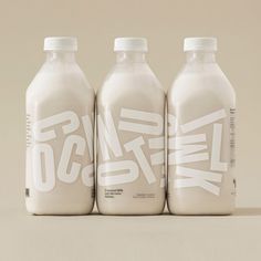 three milk bottles with white lettering on them