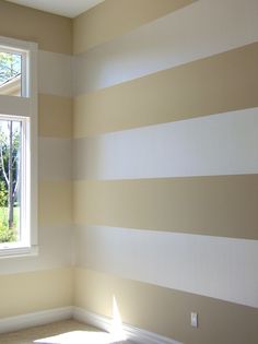 an empty room with striped walls and white trim on the wall, along with a window