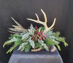 an arrangement of deer antlers, pine cones and berries in a vase on a table