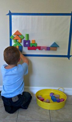 a young boy playing with wooden blocks on the wall