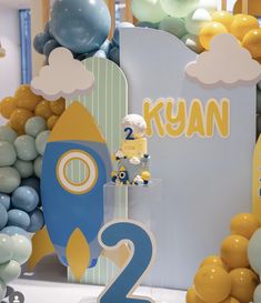 a blue and yellow rocket themed birthday party with balloons in the shape of numbers 2