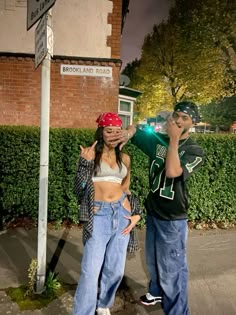 two people standing next to each other near a street sign